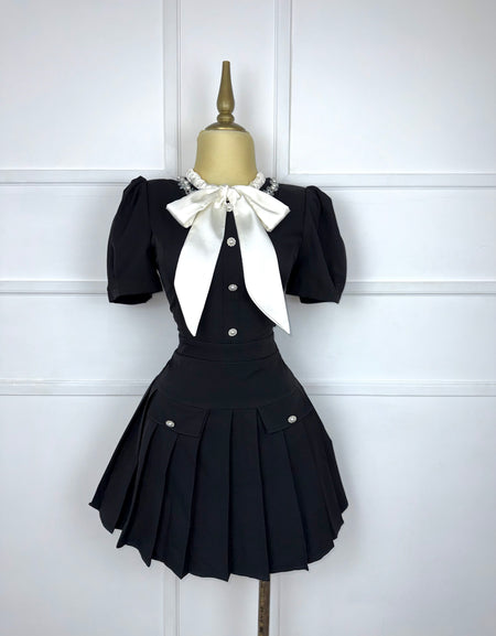 Vestido negro plisado con moño beige