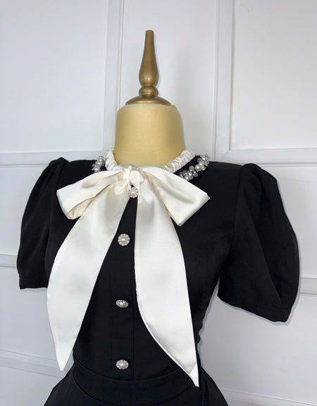 Vestido negro plisado con moño beige
