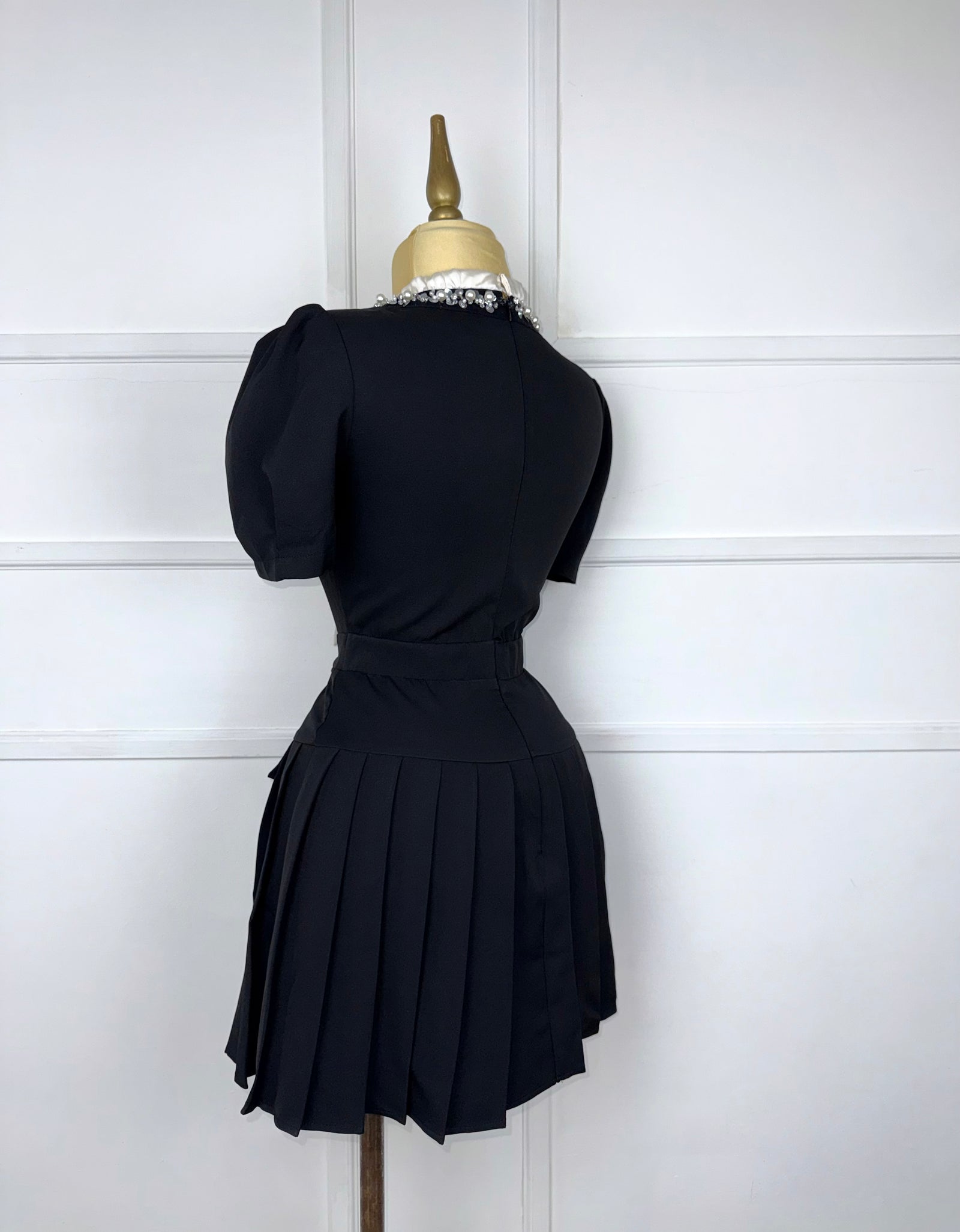 Vestido negro plisado con moño beige